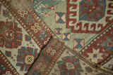 Folded antique Kazak rug corner, displaying rare green field, worn pile, and wide geometric borders.