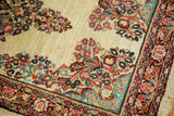 Detailed floral sprays and tropical colors on the ivory field and border of a fine Vintage Sarouk rug.