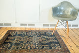 Antique Farahan Sarouk rug's navy field, sprawling floral bouquets, and worn burnt brick border.