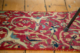 Antique Kerman fragment with intricate floral and vine design on a rich ruby red field.