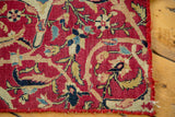 Storied corner of an antique Kerman rug fragment, with ruby red field and intricate floral vines.