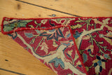 Folded antique Kerman rug revealing hand-knotted foundation and ruby red curvilinear motifs.