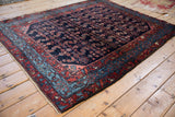 Vintage Engelas rug from an angle, highlighting the lustrous navy wool and colorful borders.
