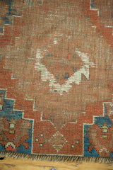 Distressed antique Caucasian rug close-up, flat pile, visible red wefting, Qashqai-style corner motif.