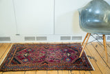 Ruby purple Lilihan rug field with mirrored floral planters and brilliant blue border.