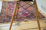 Vintage Lilihan rug corner with brilliant blue border, ruby purple field, and white fringe.