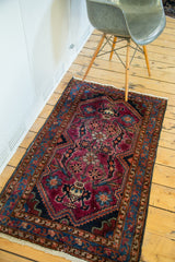 Vintage Lilihan rug corner: ruby purple field, brilliant blue border, mirrored planter motifs.