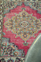 Slate blue corner spandrel with ornate floral patterns on a raspberry vintage Meshed rug.