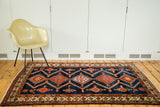 Northwest Persian rug with deep indigo field, serrated rectilinear medallions, and visible abrash.