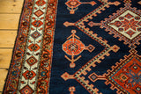 Close-up of vintage Northwest Persian rug's geometric border, deep indigo field with orange, blue serrated motifs.
