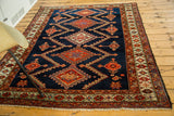 Deep indigo field with orange serrated motifs and detailed geometric border of this vintage Persian rug.