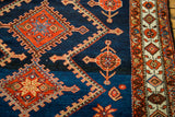 Vintage Persian rug detail: indigo abrash, orange medallions, and patterned border.
