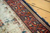 Distressed ivory field and red geometric border on an antique Lilihan runner.