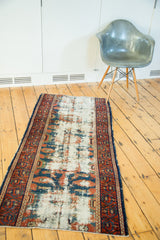 Distressed ivory and blue field of an antique Lilihan runner, framed by a rust-colored border.