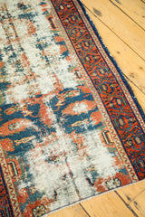 Antique Lilihan runner with distressed ivory field, blue and rust floral remnants, geometric border.