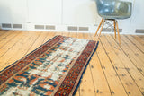 Distressed field of antique Lilihan runner, showing ivory foundation with faded blue and coral motifs.