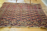 Antique Turkmen Chuval rug's geometric border, featuring small animal motifs, terracotta hues, and delicate fringe.
