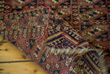 Antique Turkmen Chuval rug corner folded, revealing geometric guls and time-softened hues.
