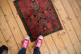 Cherry red vintage Mohajeran Sarouk rug, blue laurel wreath pattern, with red sneakers.