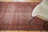 Antique Doroksh rug's distressed red and bronze pattern, styled with a modern chair.