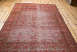 An angled view showing the time-softened texture of a smokey red antique Doroksh rug.