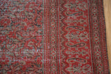Storied wear on the smokey red and charcoal bronze vine and leaf motif of an antique rug.