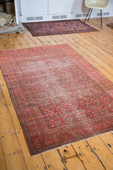 Antique Persian Doroksh rug with distressed character, shown styled in a room.