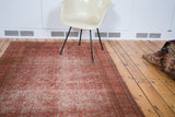 A styled antique Doroksh rug, highlighting its distressed character and smokey red, allover vine pattern.