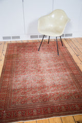 Distressed antique Doroksh rug with smokey red tones styled in a modern, minimalist interior.