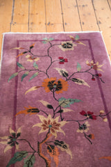 Sprawling floral vines and thin banded border on the mauve purple vintage Art Deco rug.