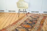 Tattered antique Caucasian runner with geometric patterns in blue, orange, and red.
