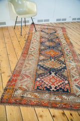 Detail of the distressed antique Caucasian rug, featuring geometric medallions and fringed end.