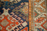 Distressed geometric blue, orange, and ivory patterns near the antique Caucasian runner's border.