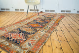 Distressed edge of antique Caucasian runner with geometric patterns in orange, red, blue.