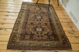 Antique Belouch rug featuring geometric triple medallions, intricate borders, and allover wear.