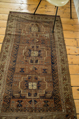 Distressed geometric medallions in ivory, brown, and navy on an antique Belouch rug.