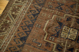 Antique Belouch rug detail showing geometric motifs and distressed wool pile in rust, navy, and beige.