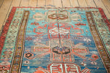 Antique Caucasian rug: geometric design in coral, grey, bronze, and vibrant blue-green abrashes.