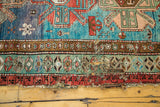 Visible wear, patches, and holes along the unique outer border of the antique Caucasian rug.