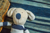 Natural Kids Toy Dog featuring its beige head, blue nose, stitched smile, and blue striped shirt.