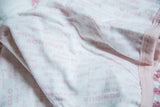 Organic cotton fabric detail with soft pink text pattern and ribbed trim.