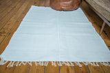 Handmade organic cotton white rag rug with visible woven texture and fringes.