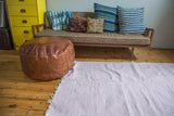 Soft pink and white organic cotton rag rug with subtle chevron pattern and white fringe.