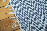 Navy and white geometric weave of an organic cotton rag rug with visible fringe.