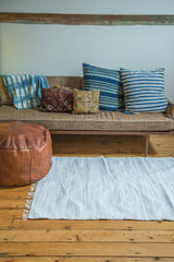 Minimalistic organic cotton rag rug in light gray and white, showing ribbed texture and fringe.