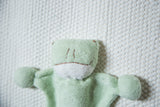 Close-up of the pale green organic cotton baby frog, highlighting its plush texture and embroidered face.