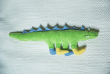 Head of green organic cotton dinosaur toy with blue spikes and tiny teeth.