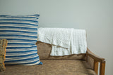Unbleached white organic cotton cable knit blanket draped, highlighting its soft texture.