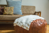 Soft natural white organic cotton cable knit blanket with ribbed hem.