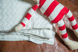 Unbleached natural white organic cotton cable knit blanket texture.